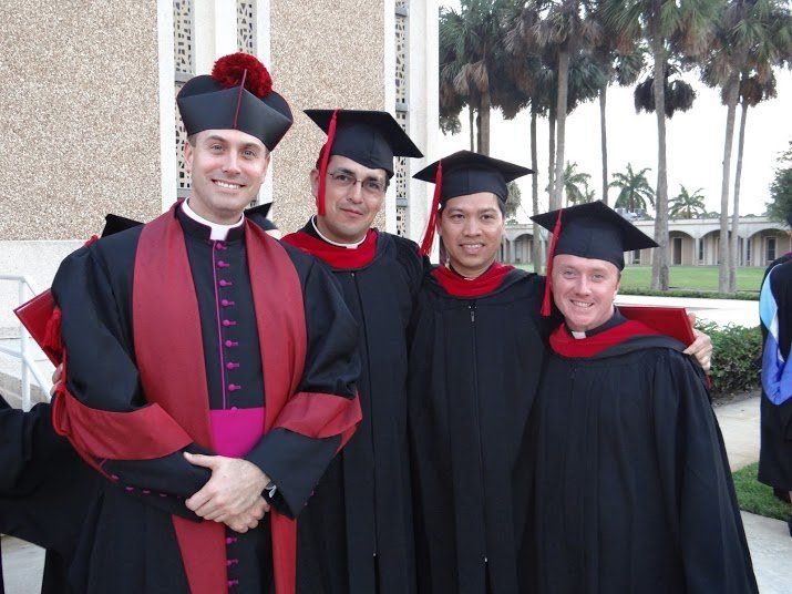 Tres graduados del seminario junto al rector.