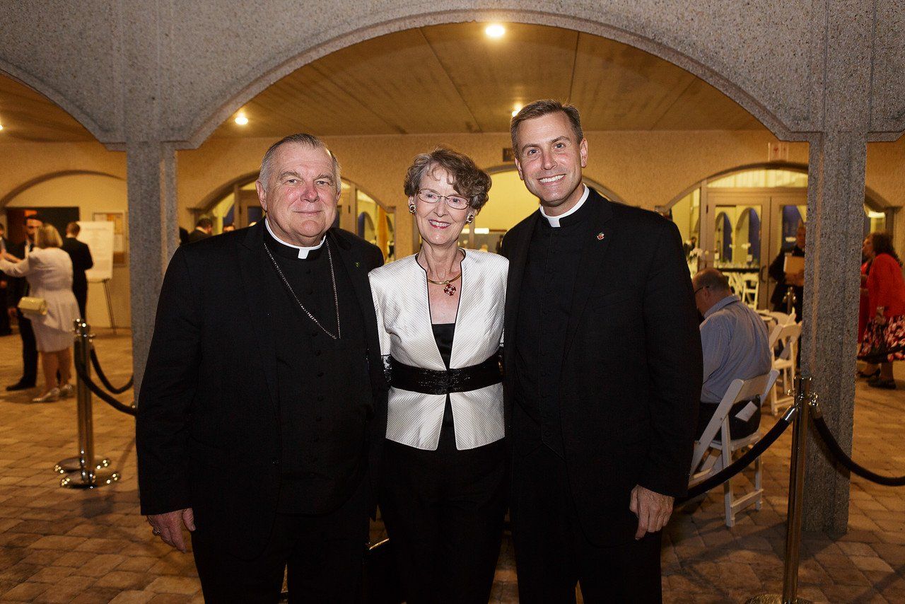 Woman posing for a photo with two priest at the event
