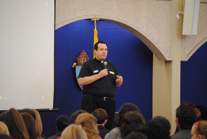 A priest speaking to group of attendees.