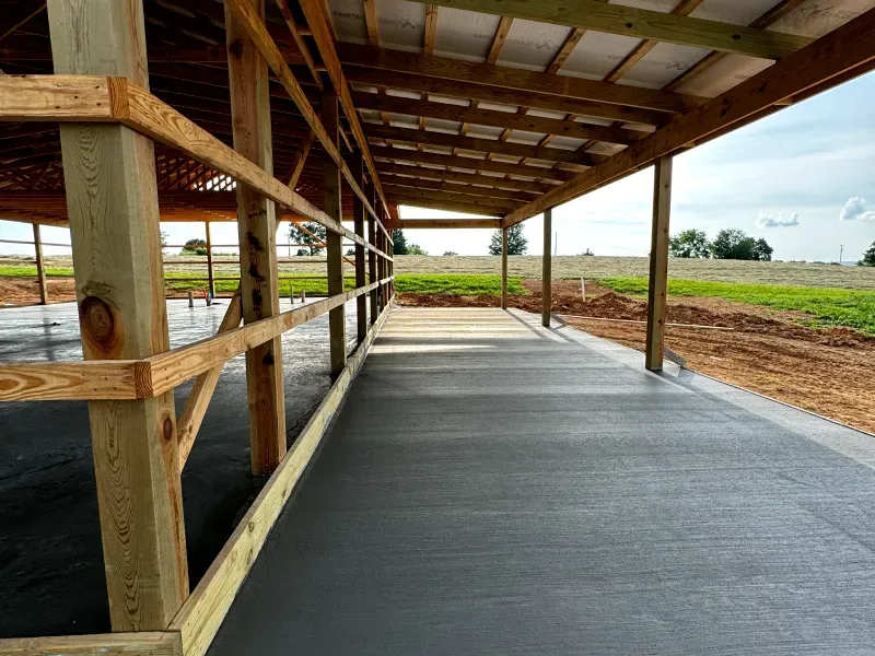 A long wooden covered walkway leading to a field.