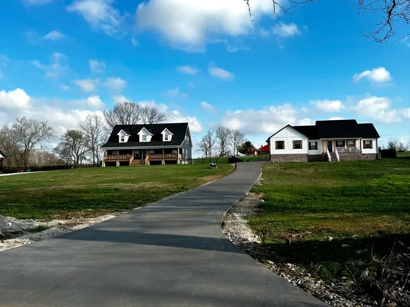 A concrete driveway leading to a house on a hill