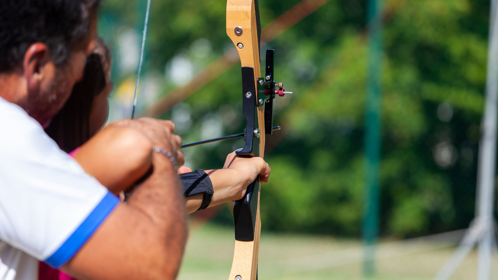 A man and a woman are practicing archery together.