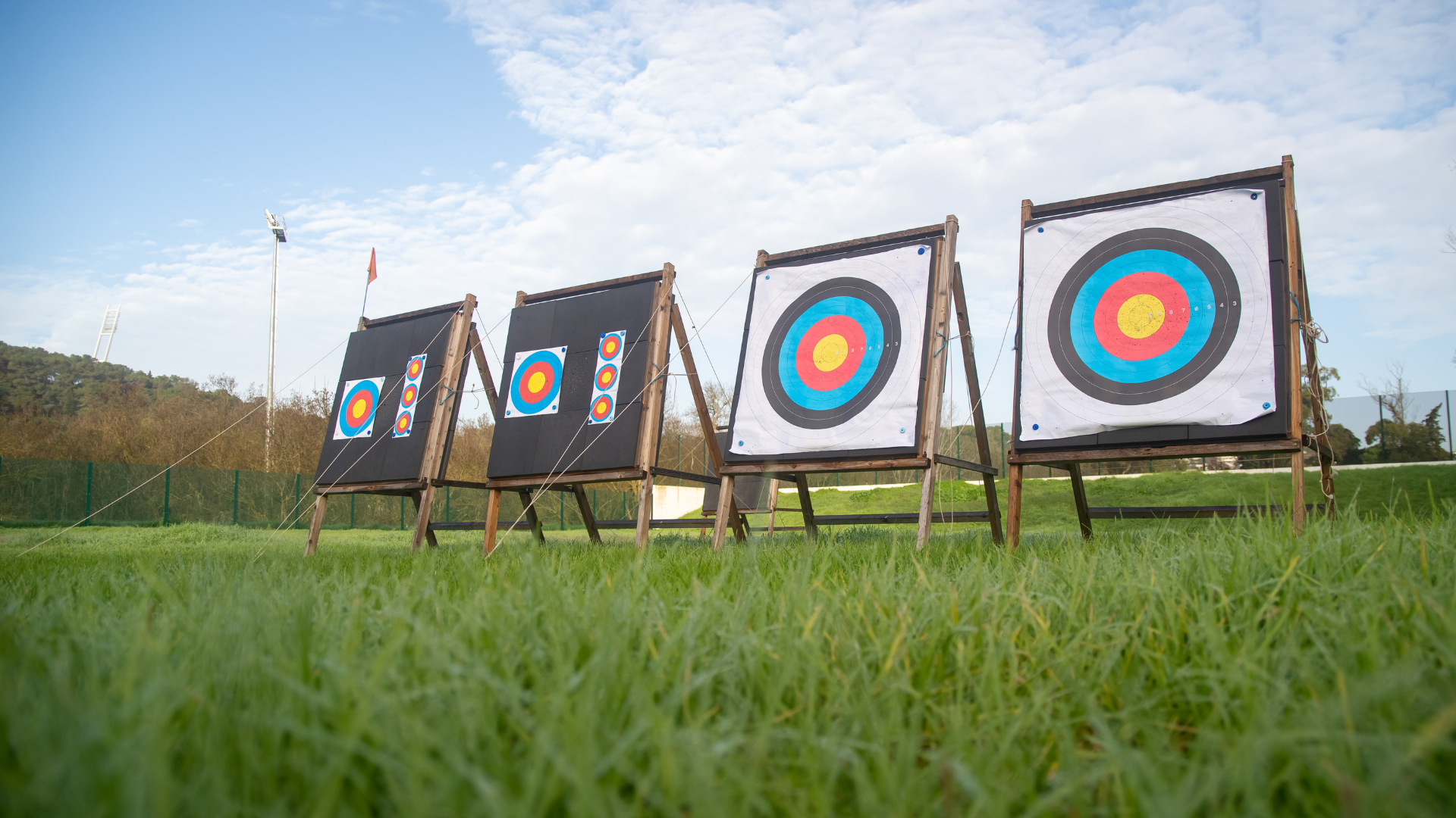 A row of archery targets sitting on top of a lush green field.