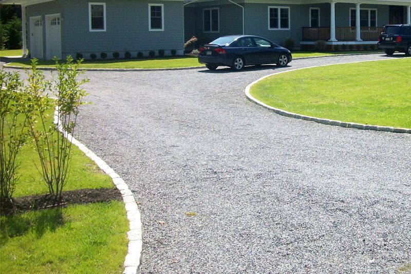 A man is using a shovel to spread gravel on a patio.