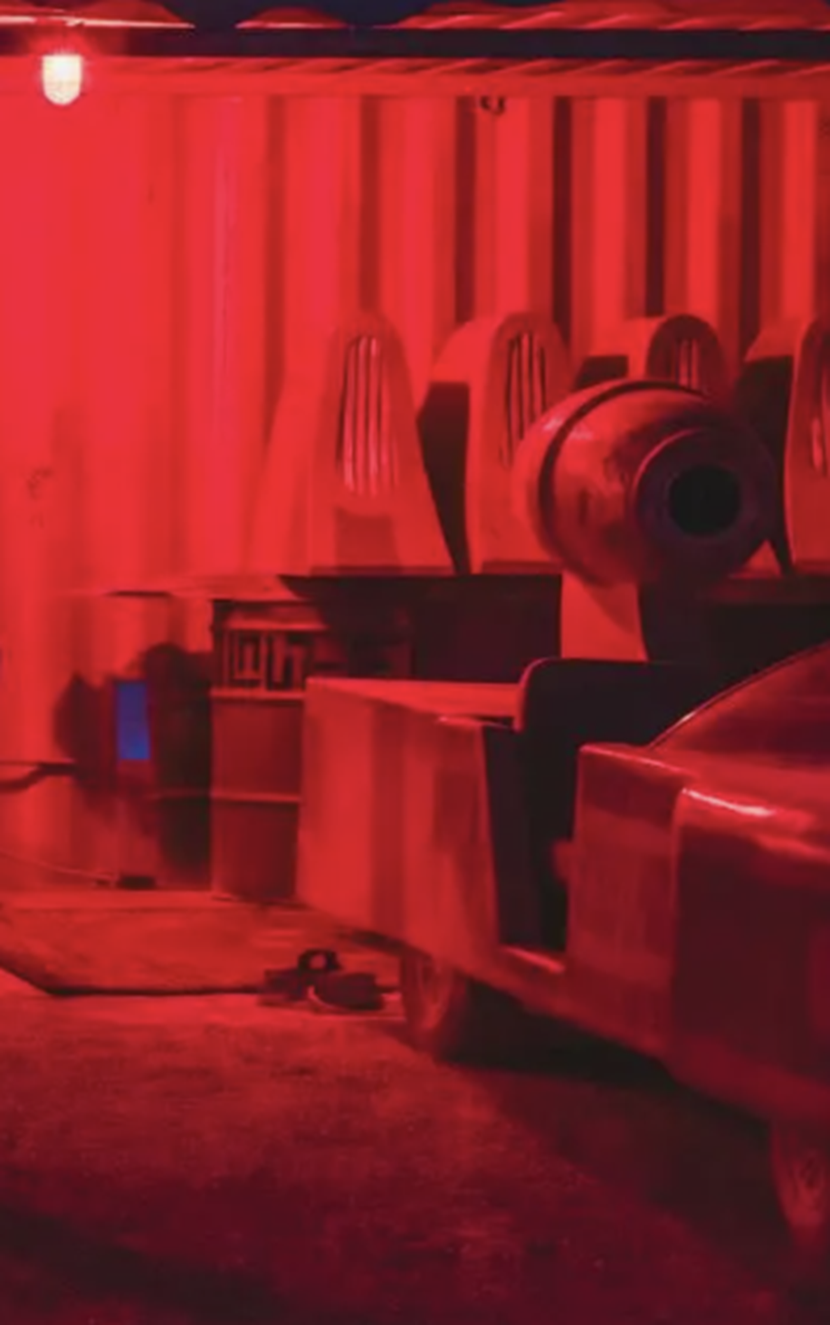 A car is parked in a dark room with red lights.