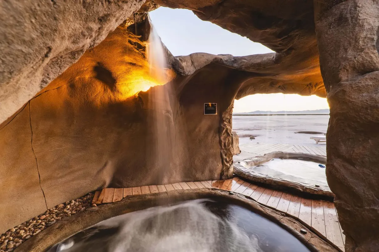 A waterfall is coming out of a cave into a pool.