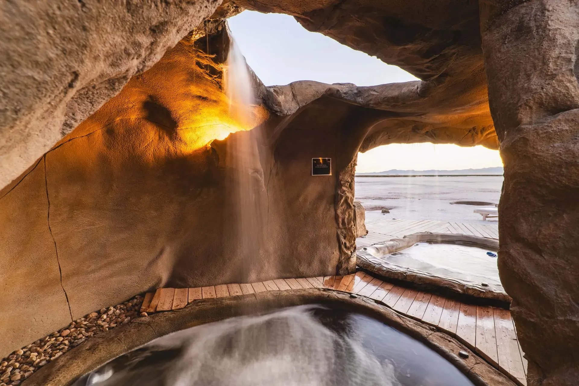 A waterfall is coming out of a cave into a pool.