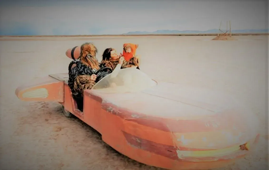 A group of people are riding in a car in the desert.