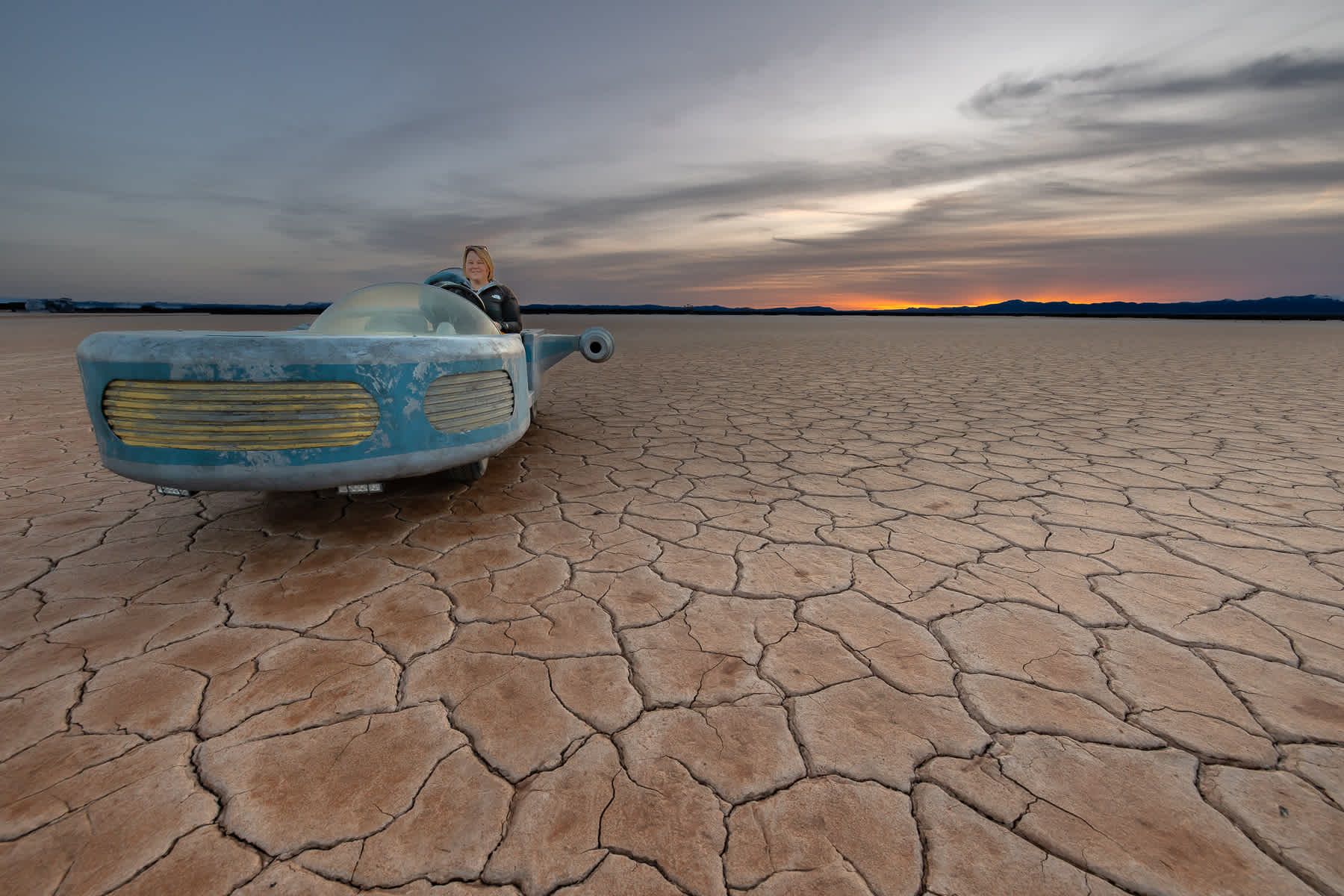 A car is parked in the middle of a desert.