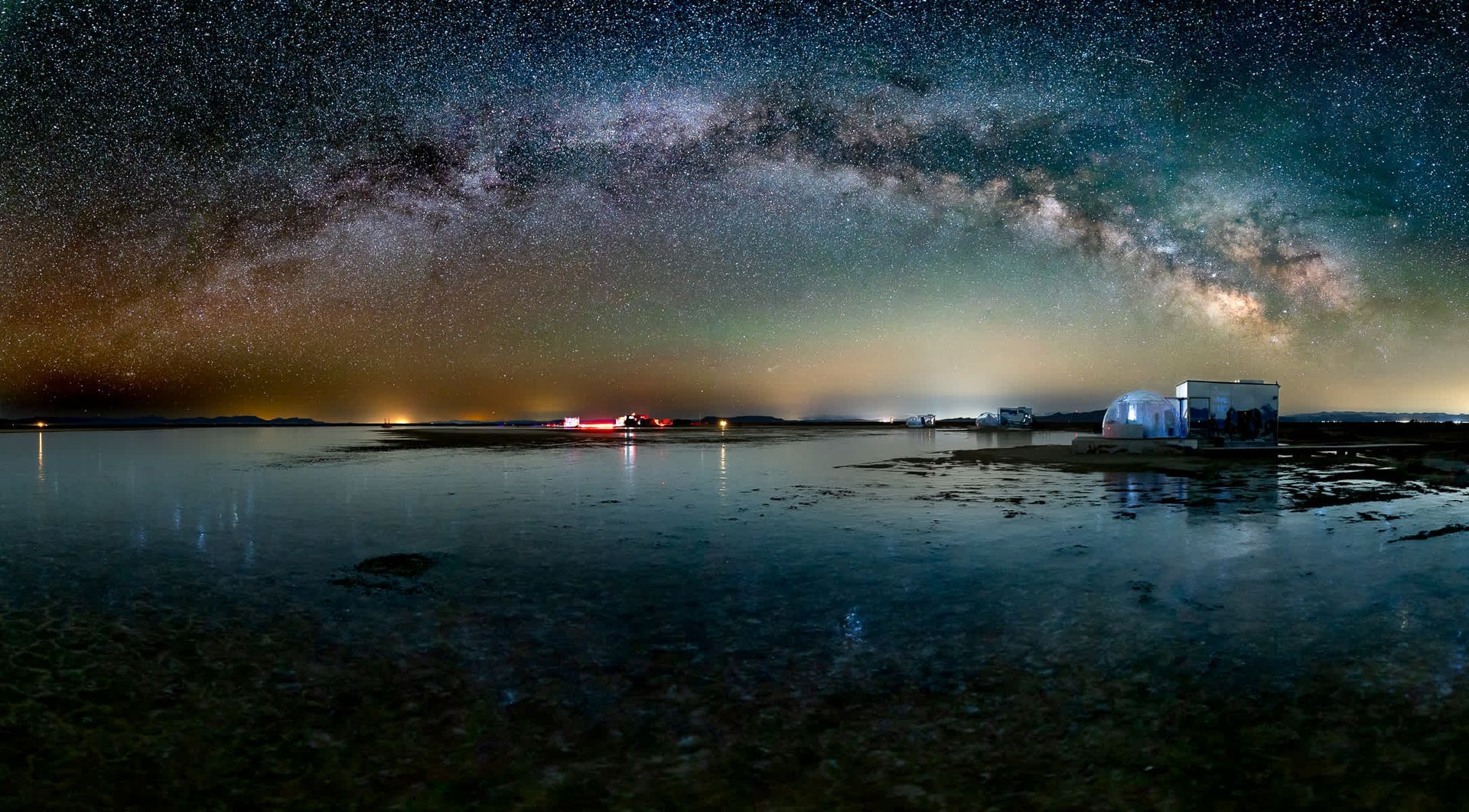 The milky way is visible over a body of water at night.