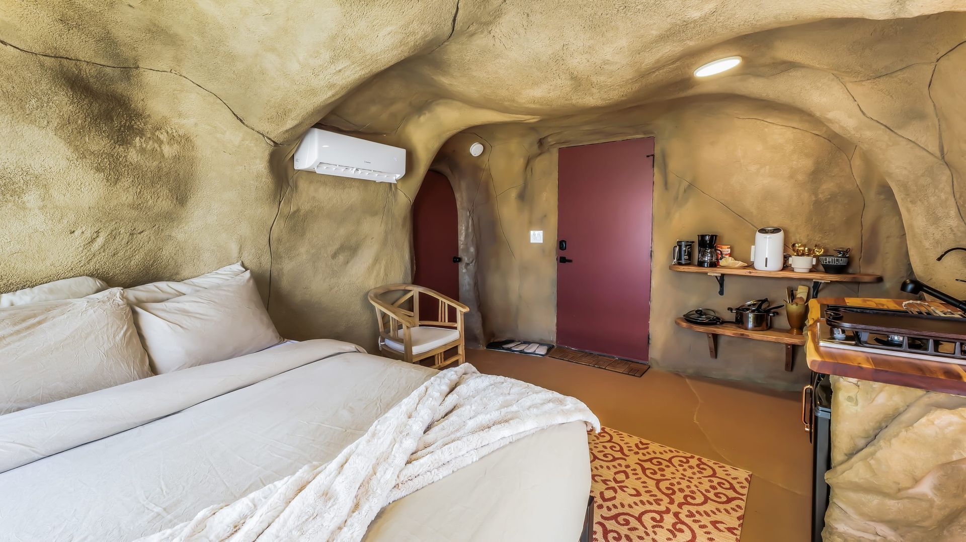 A bedroom in a cave with a bed and a chair.