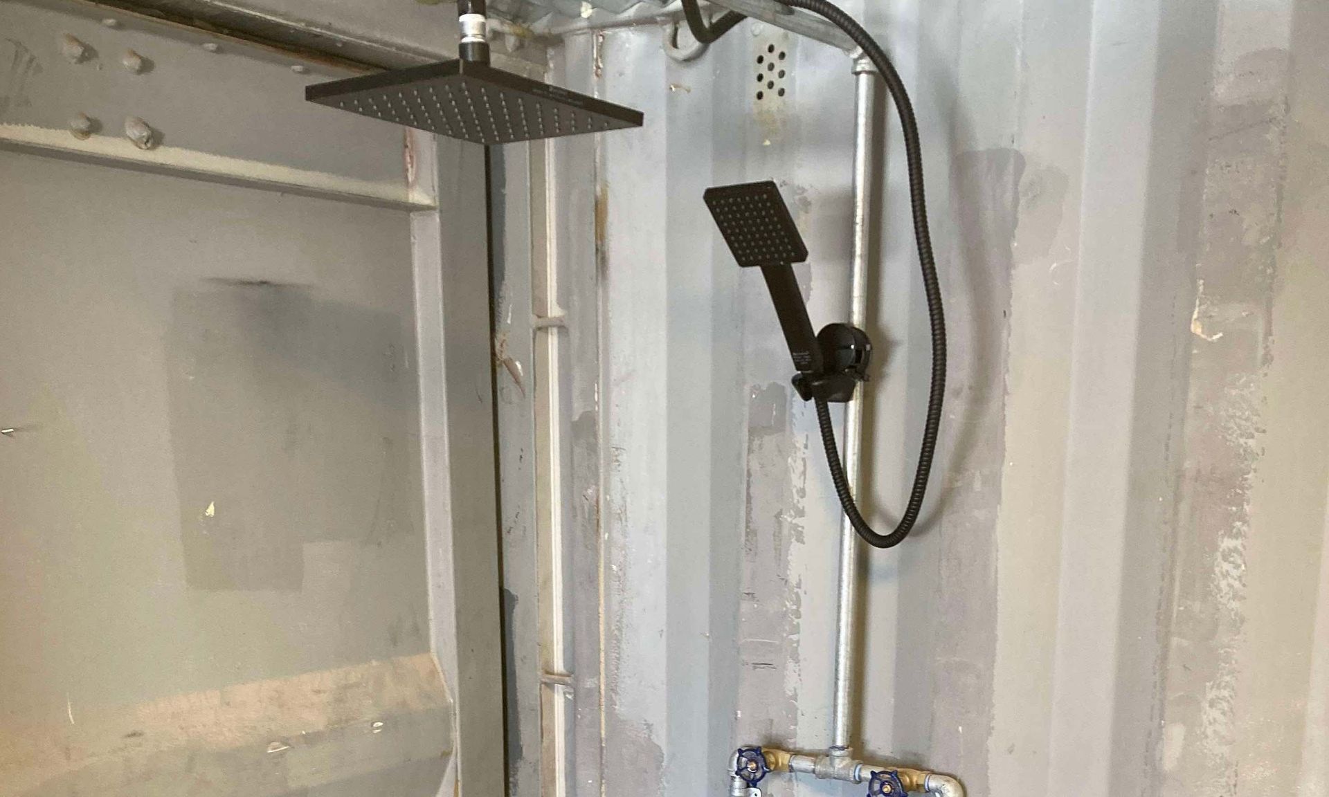 A shower head is hanging from the ceiling in a bathroom.