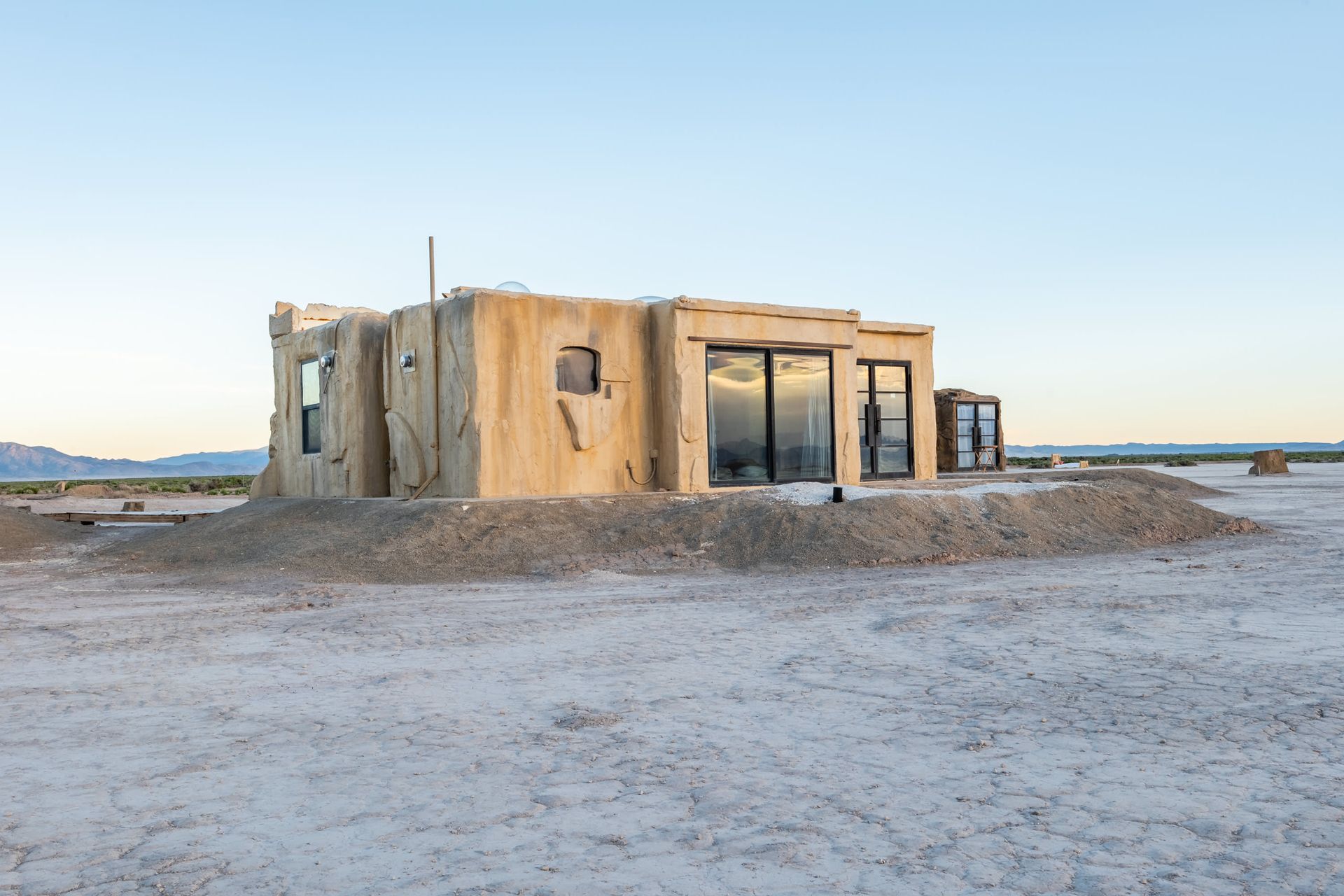 An old building is sitting on top of a pile of dirt in the middle of a desert.