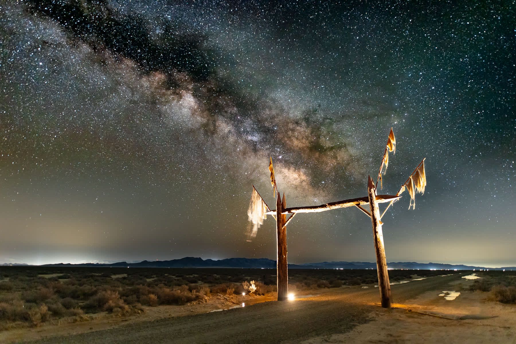 A wooden structure in the middle of a desert at night under a starry sky.