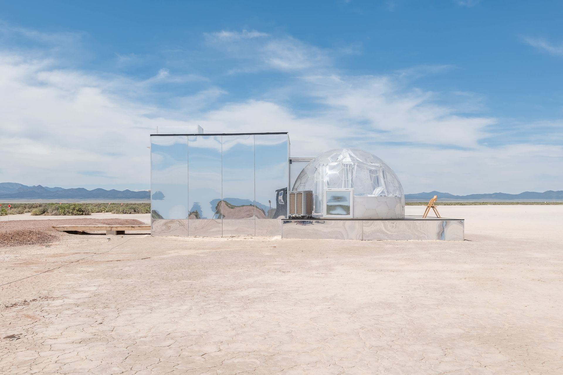 A mirrored building in the middle of a desert.