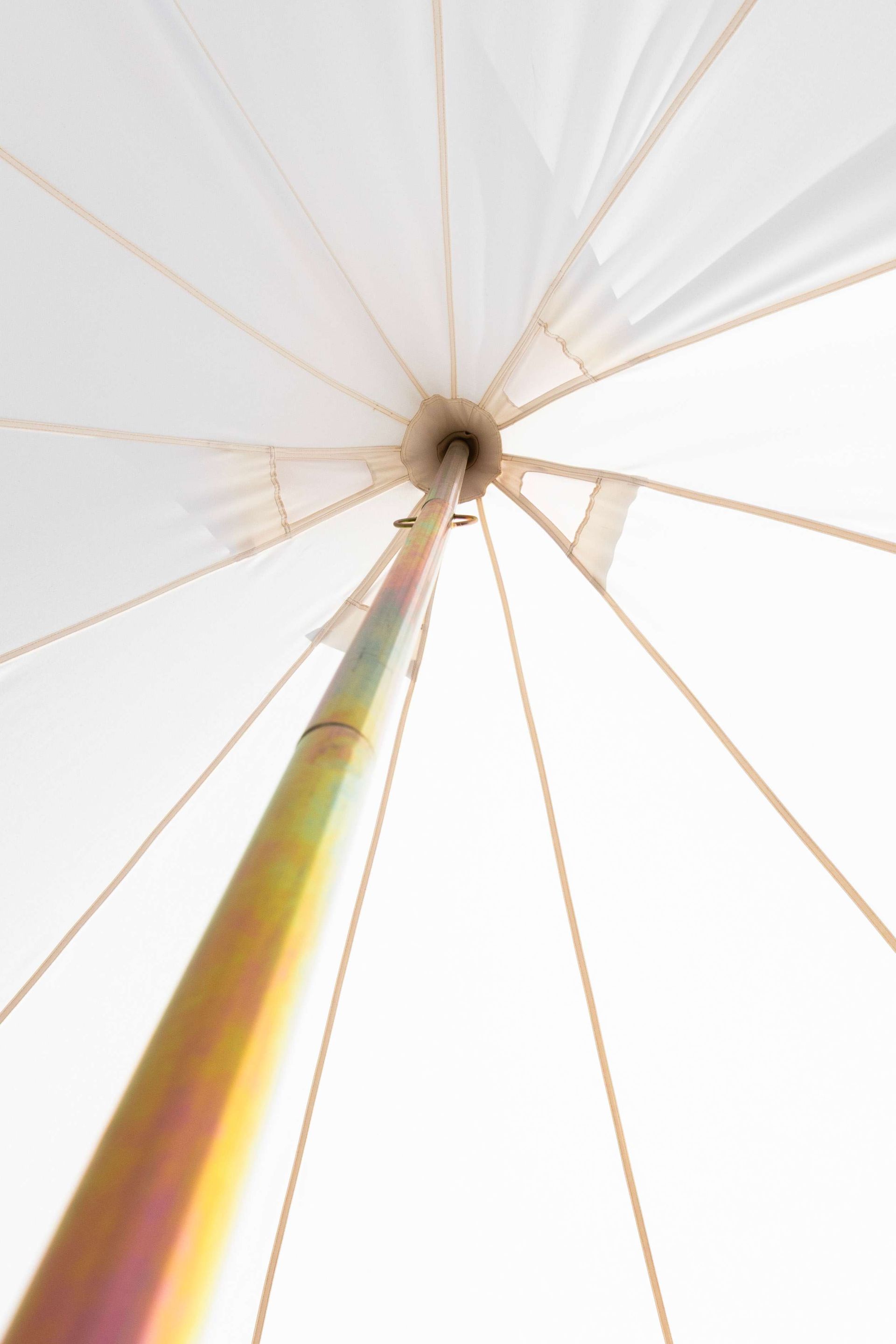 Looking up at a white tent with a yellow pole