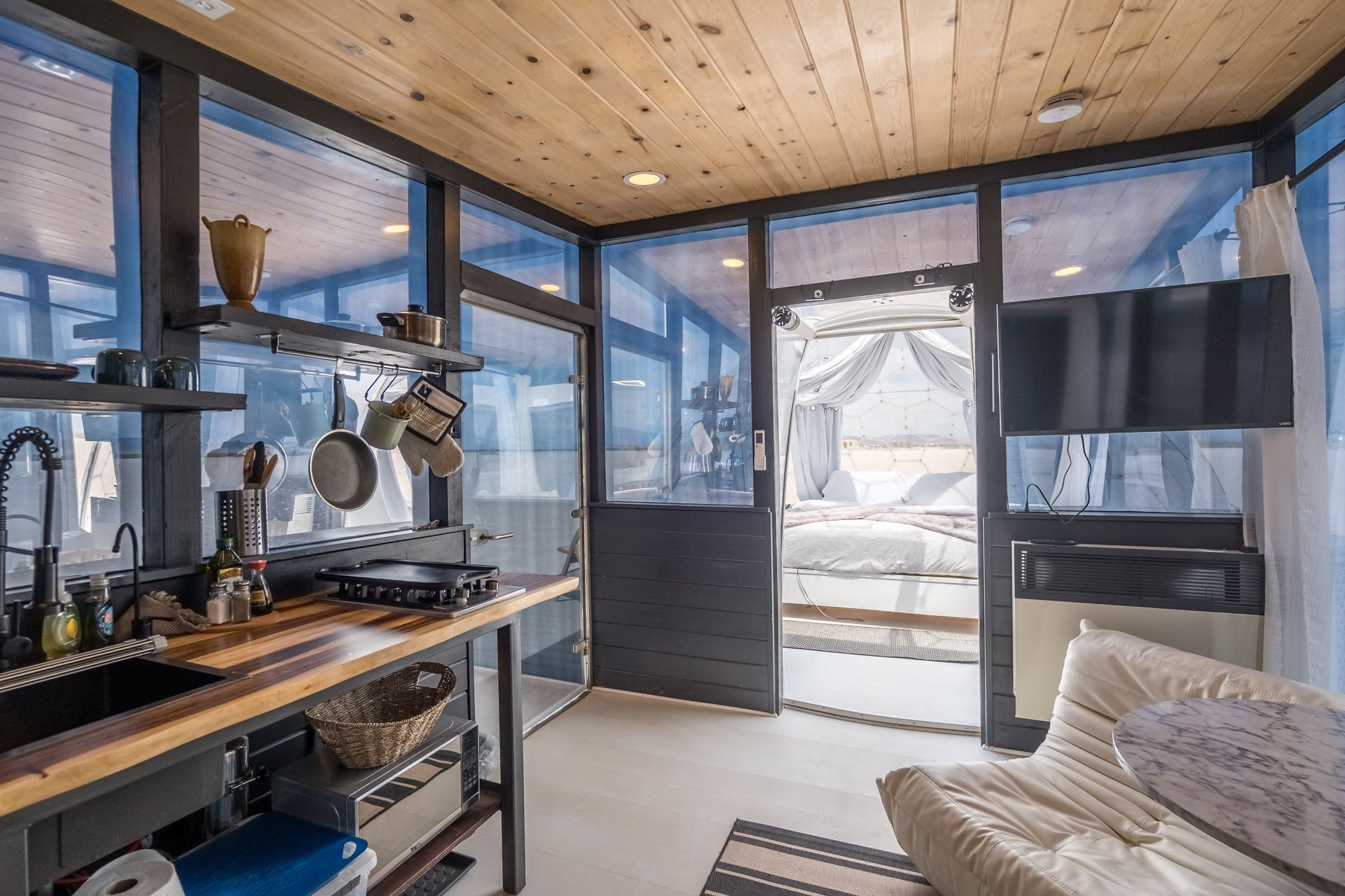 A living room with a couch and a kitchen with a lot of windows.
