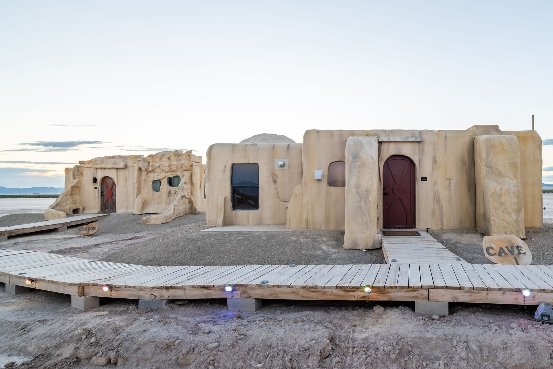 A wooden walkway leading to a building in the desert.