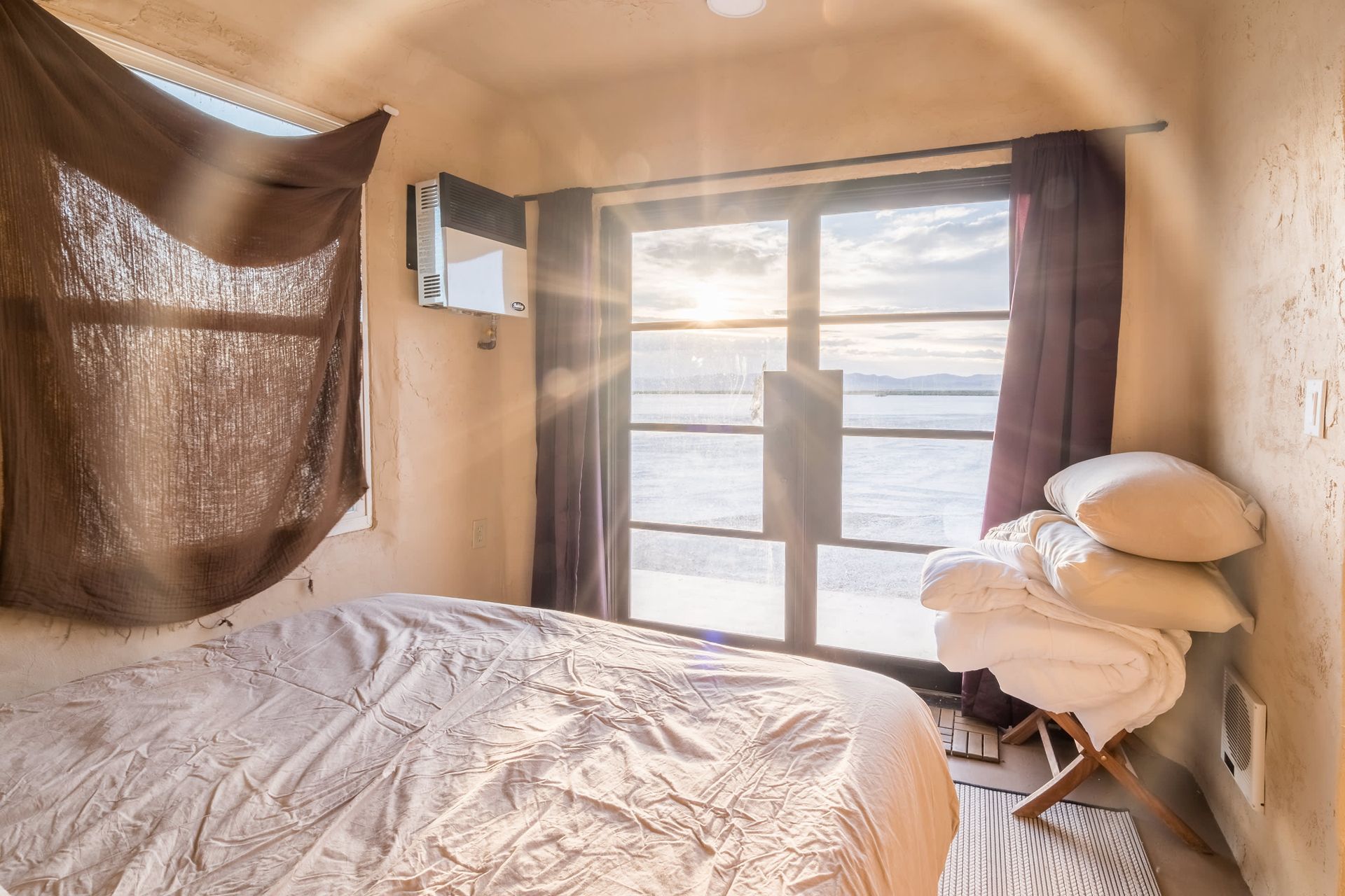 A bedroom with a bed and a window overlooking the ocean.