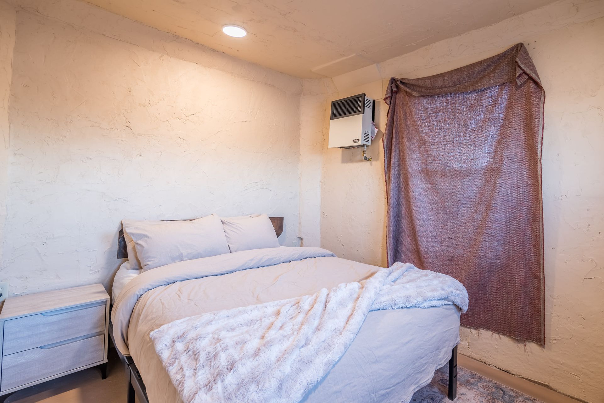 A bedroom with a bed , nightstand , and window.