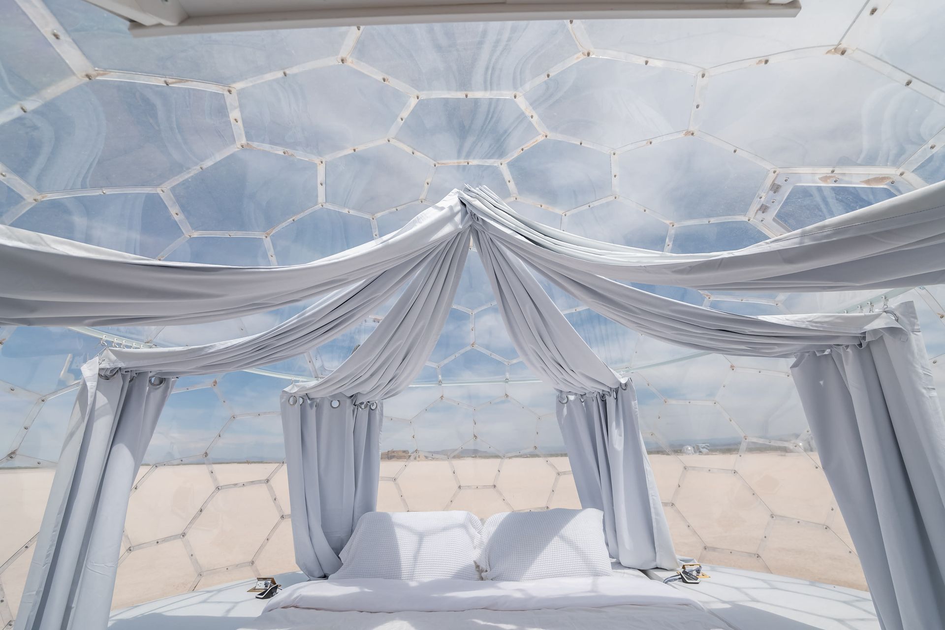 A bed in a dome with white curtains and a canopy.