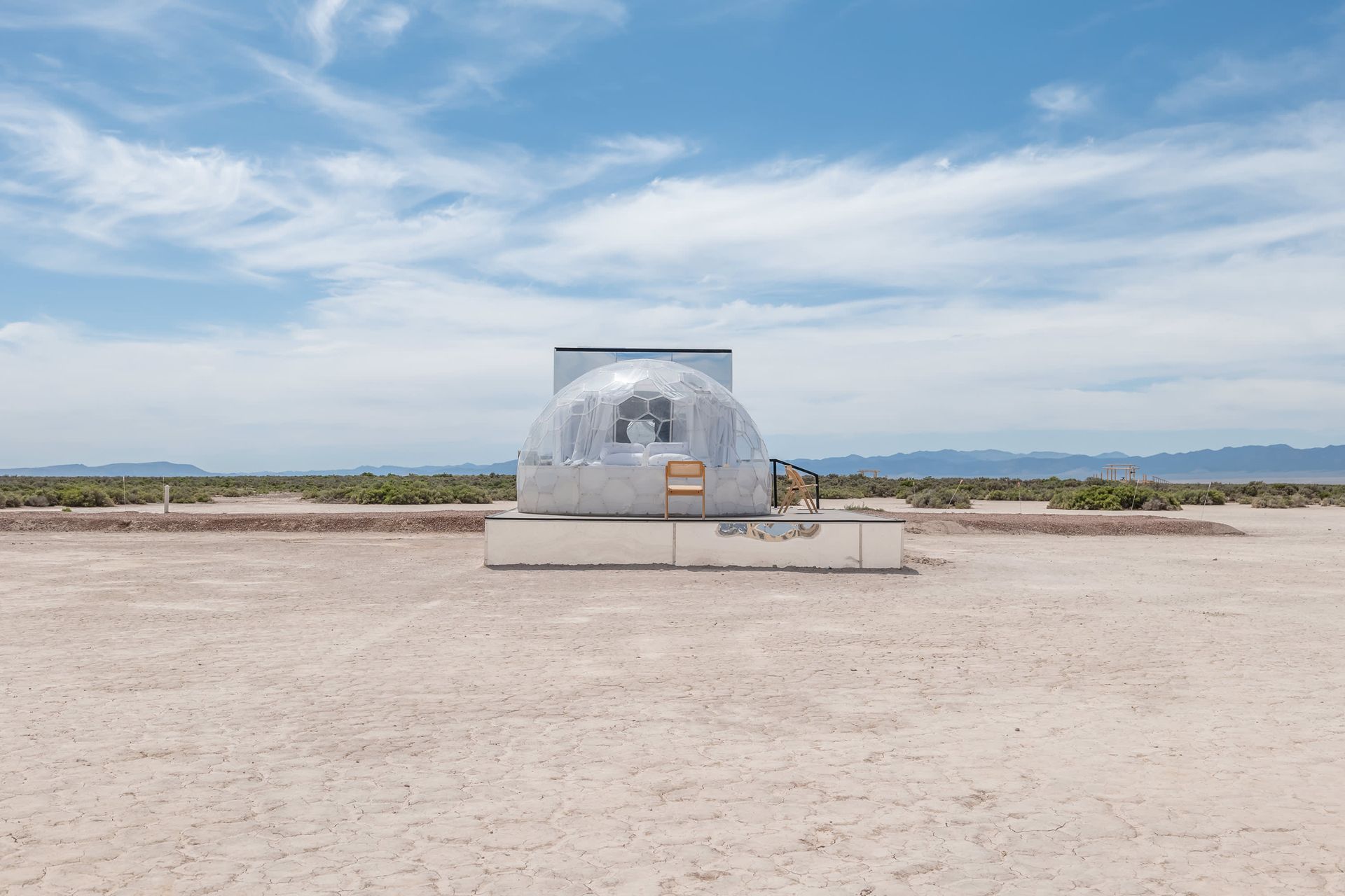 A clear dome is sitting in the middle of a desert.