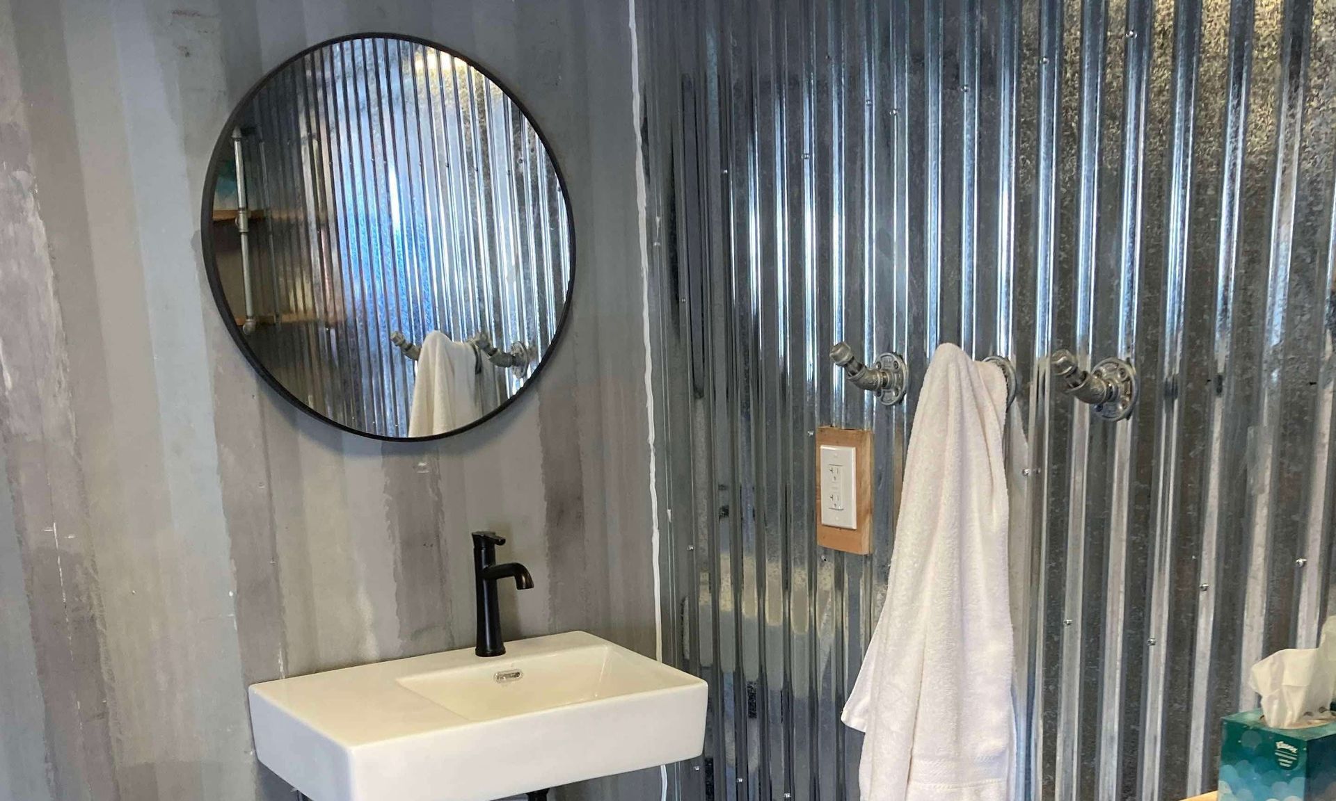 A bathroom with a sink , mirror and towels hanging on the wall.