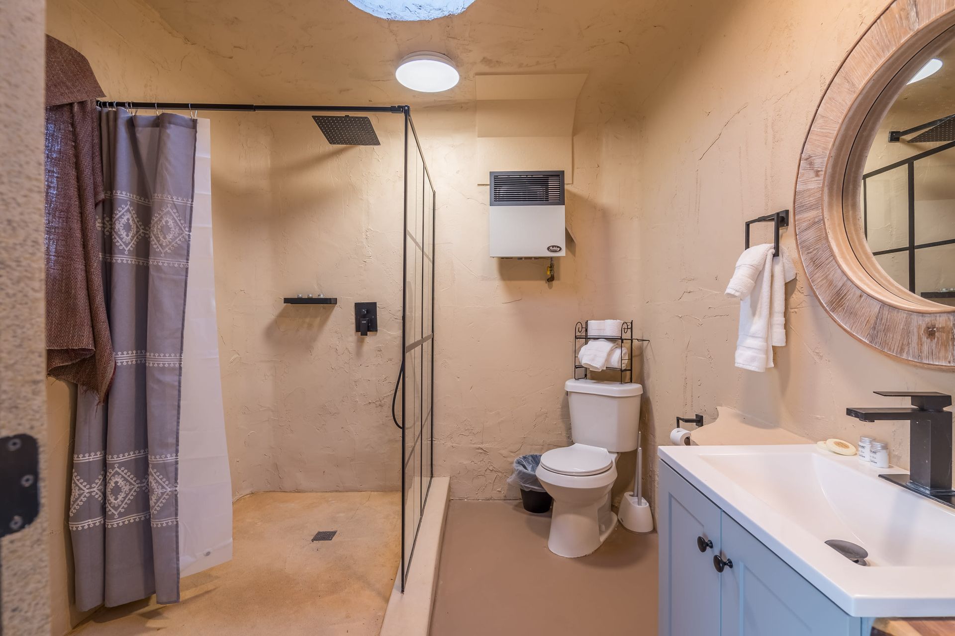 A bathroom with a toilet , sink , shower and mirror.