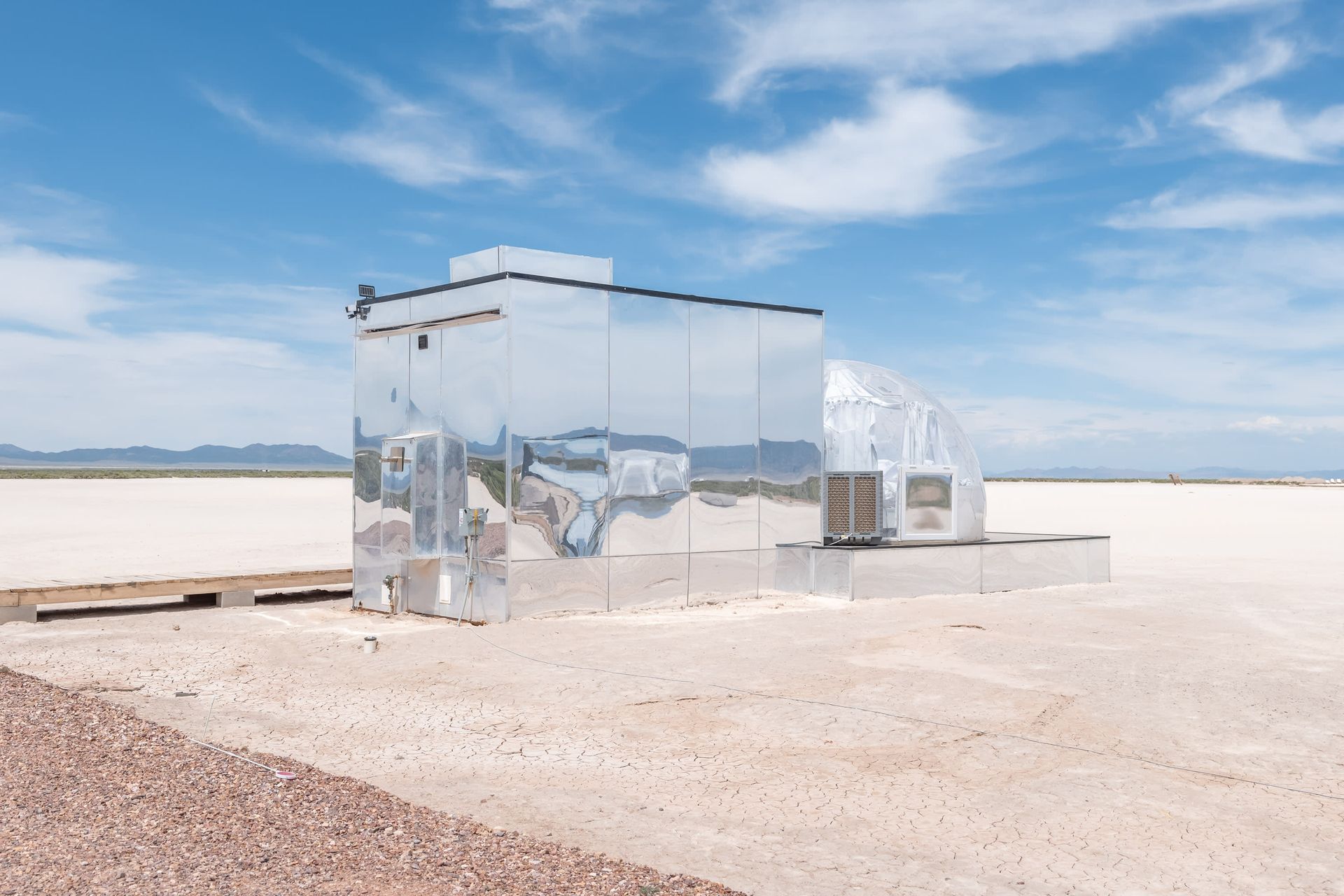 A mirrored building in the middle of a desert.