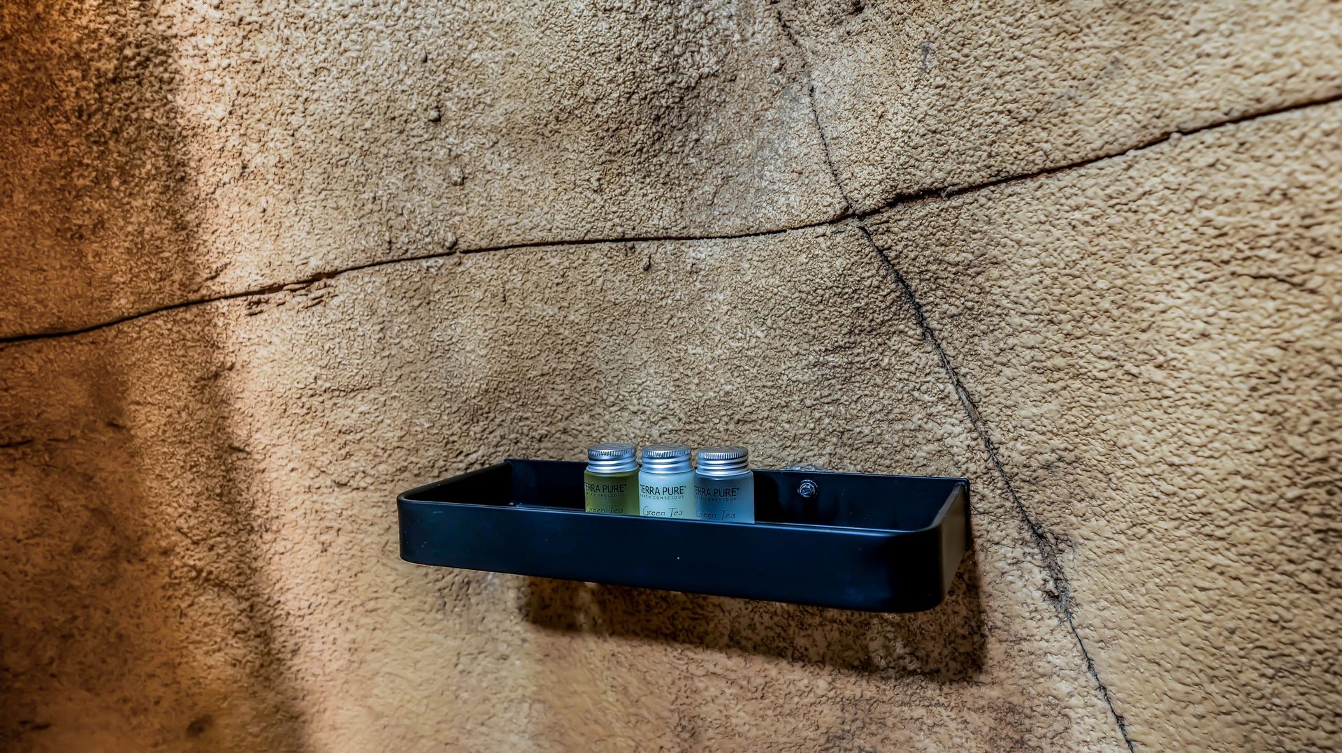 A bathroom shelf with three bottles of shampoo on it.