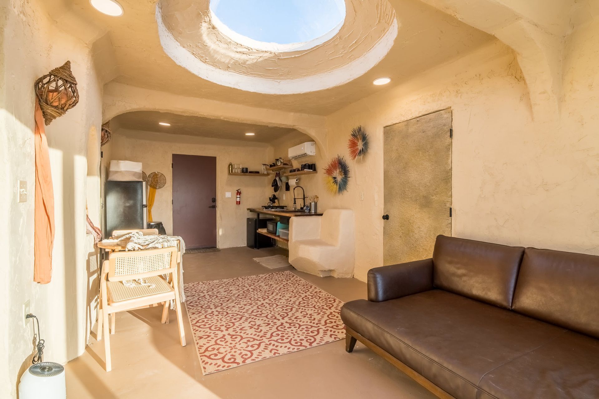 A living room with a couch , table , chairs and a skylight in the ceiling.