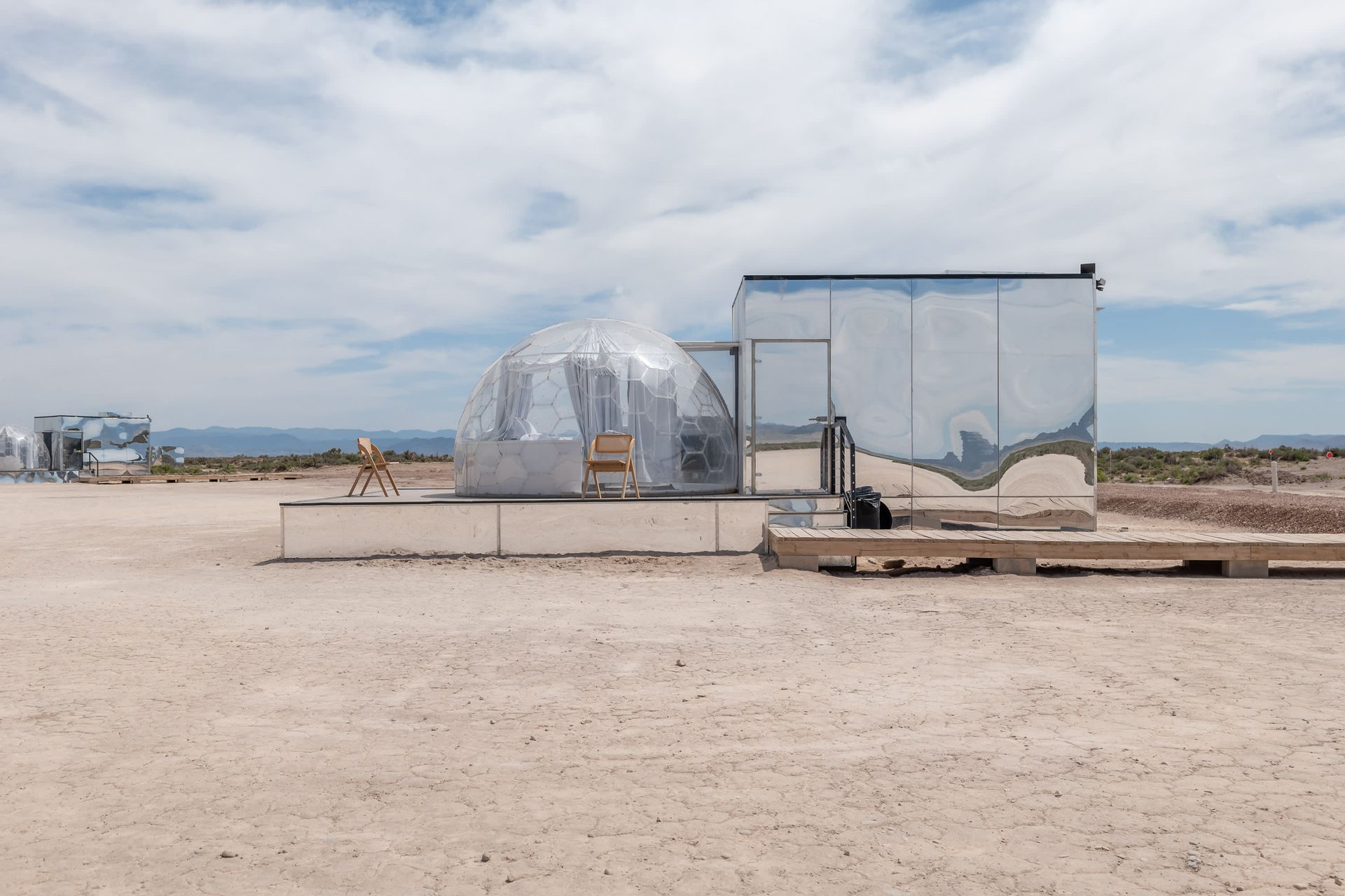 A mirrored building is sitting in the middle of a desert.