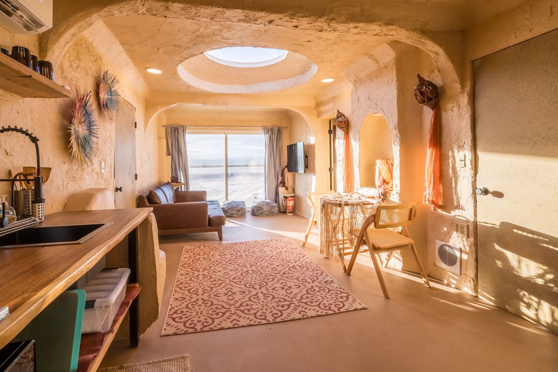 A living room with a couch , table , chairs and a sink.