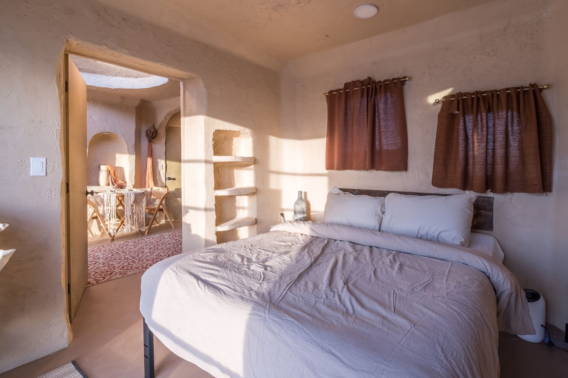 A bedroom with a bed and a bathroom in the background.