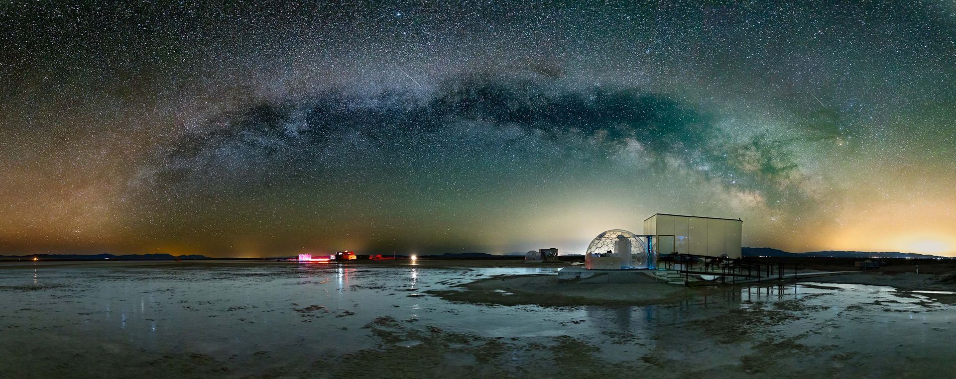 The milky way is visible in the night sky over a body of water.