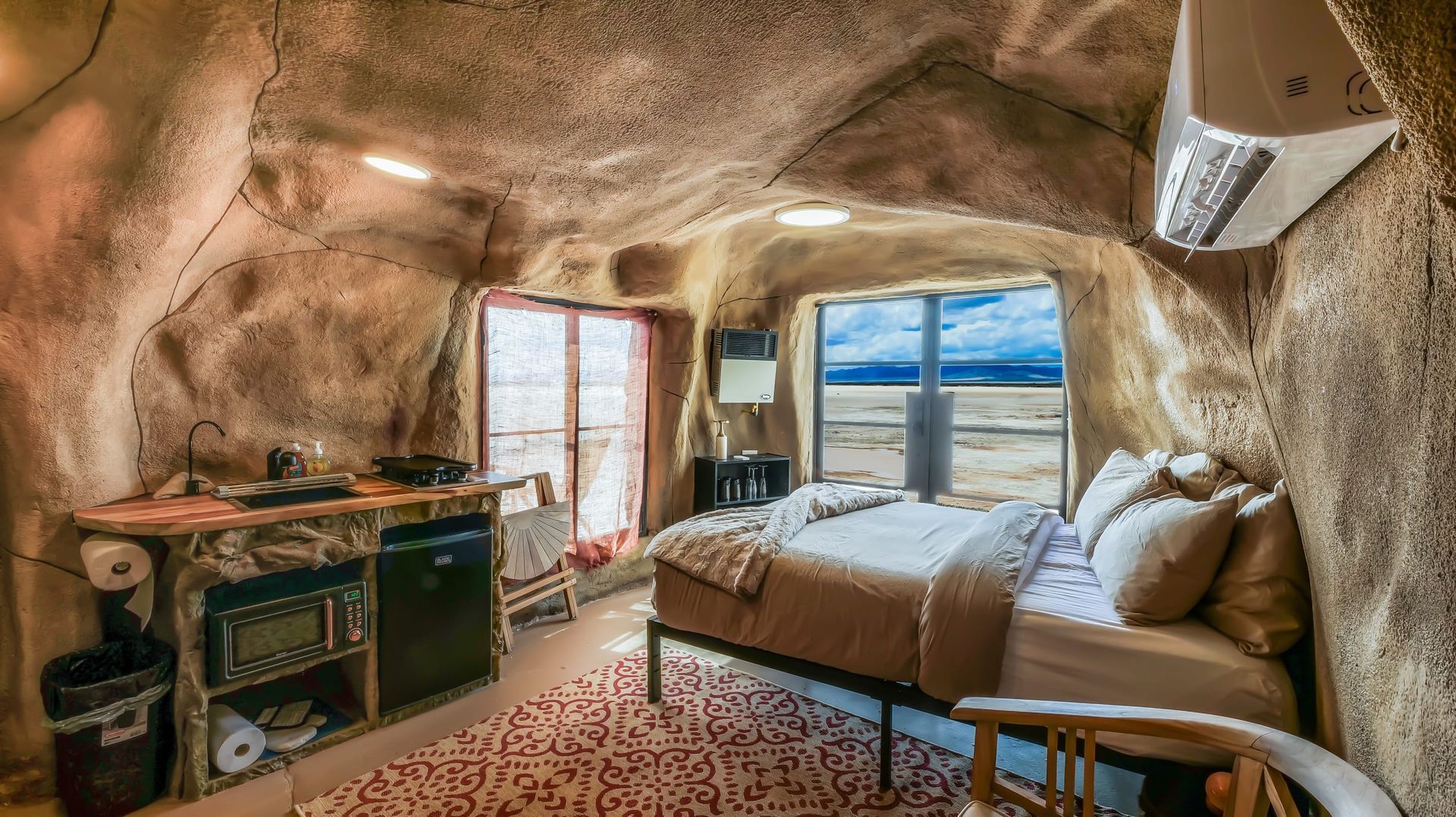 A bedroom in a cave with a bed and a chair.