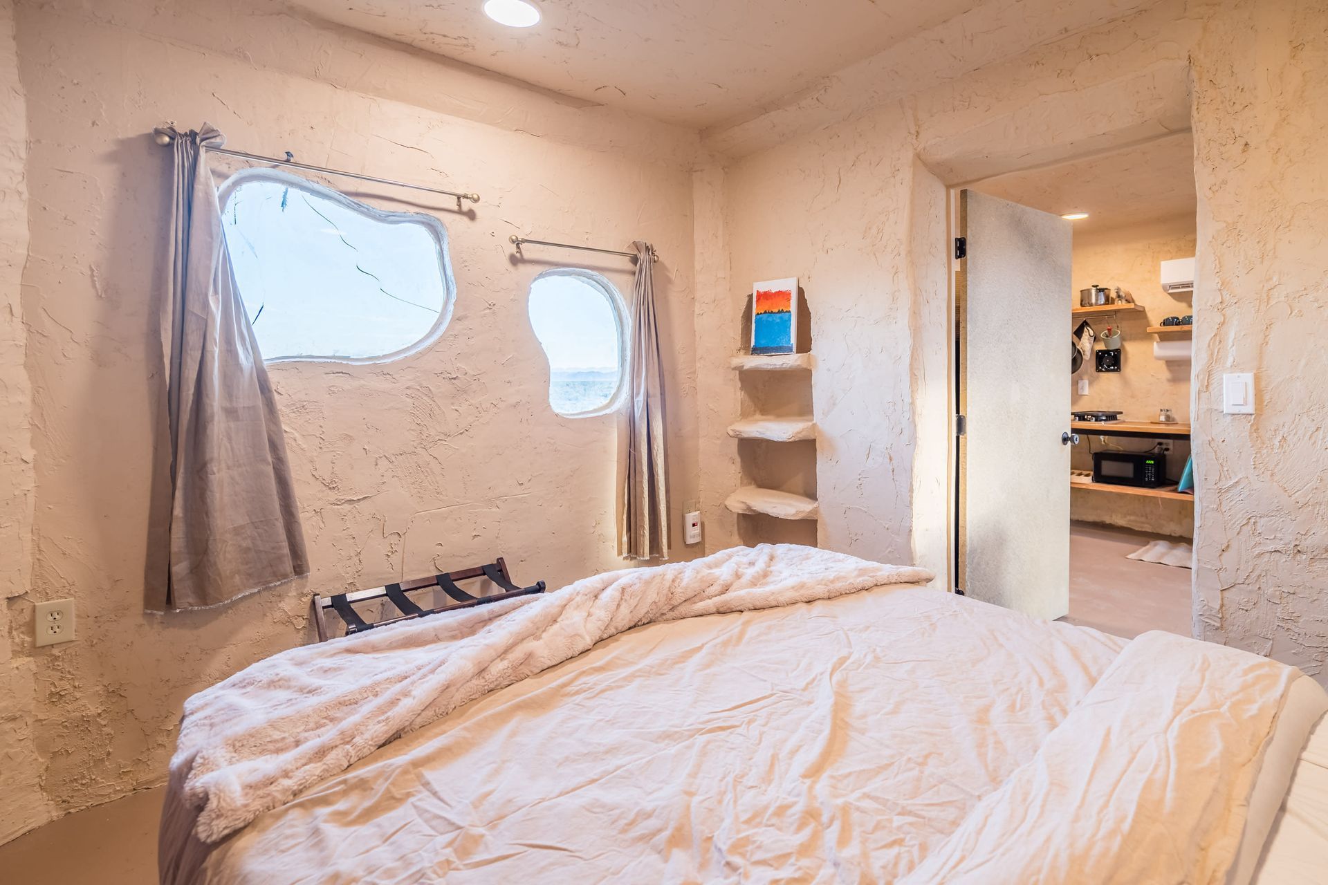 There is a bed in the middle of the room with a window.