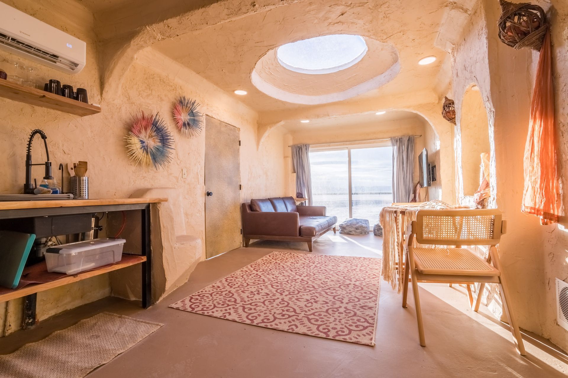A living room with a couch , table , chairs and a skylight in the ceiling.