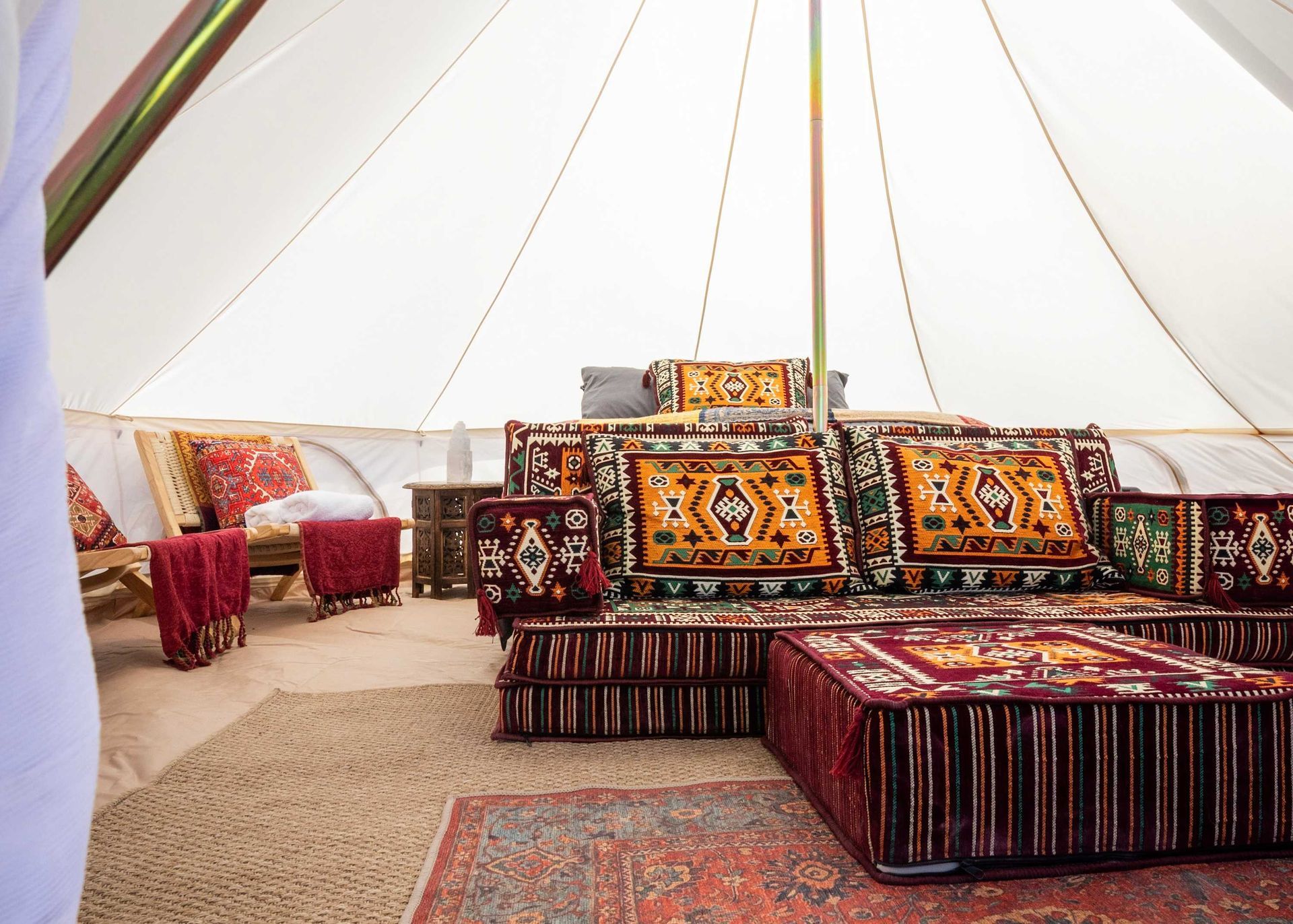 A living room with a couch , chairs , ottomans and a rug.