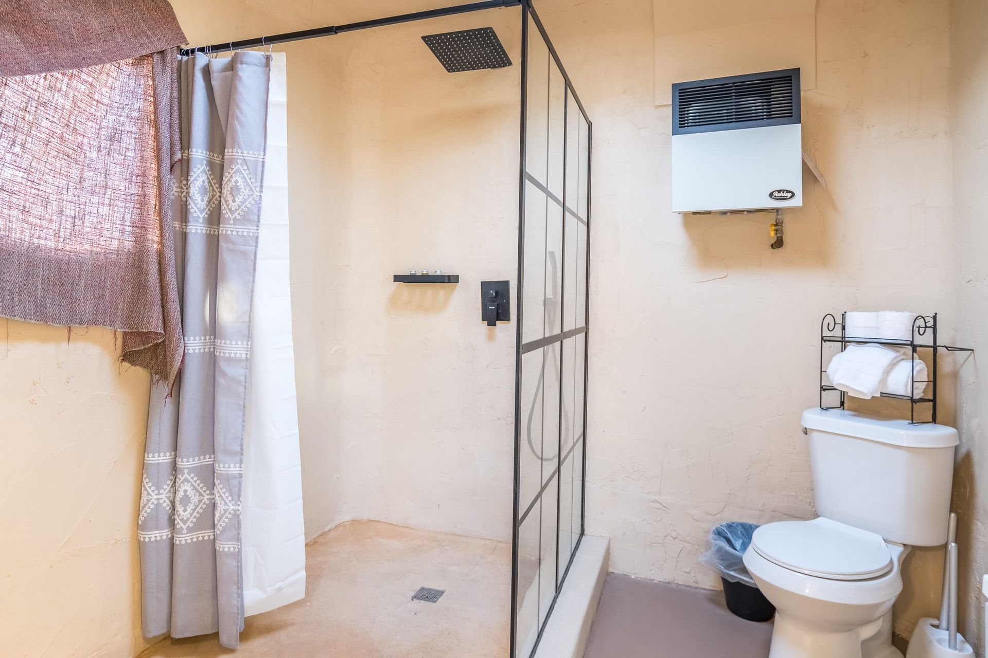 A bathroom with a toilet , shower , and heater.
