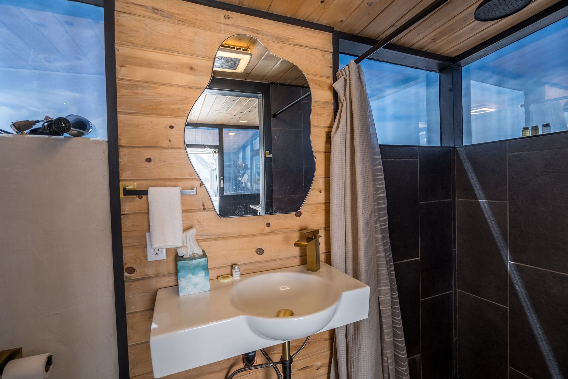 A bathroom with a sink , mirror and shower.
