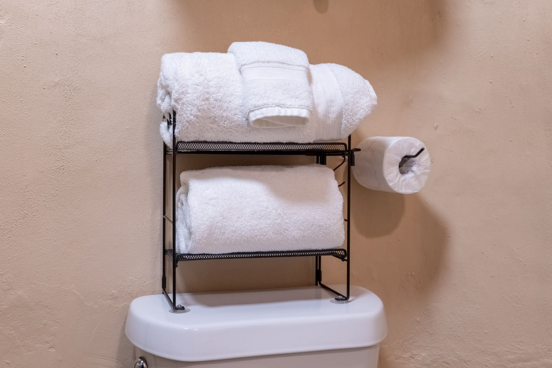 Towels are stacked on top of a toilet in a bathroom.