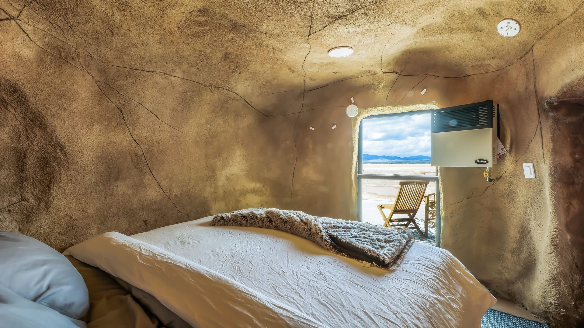 A bedroom in a cave with a bed and a window