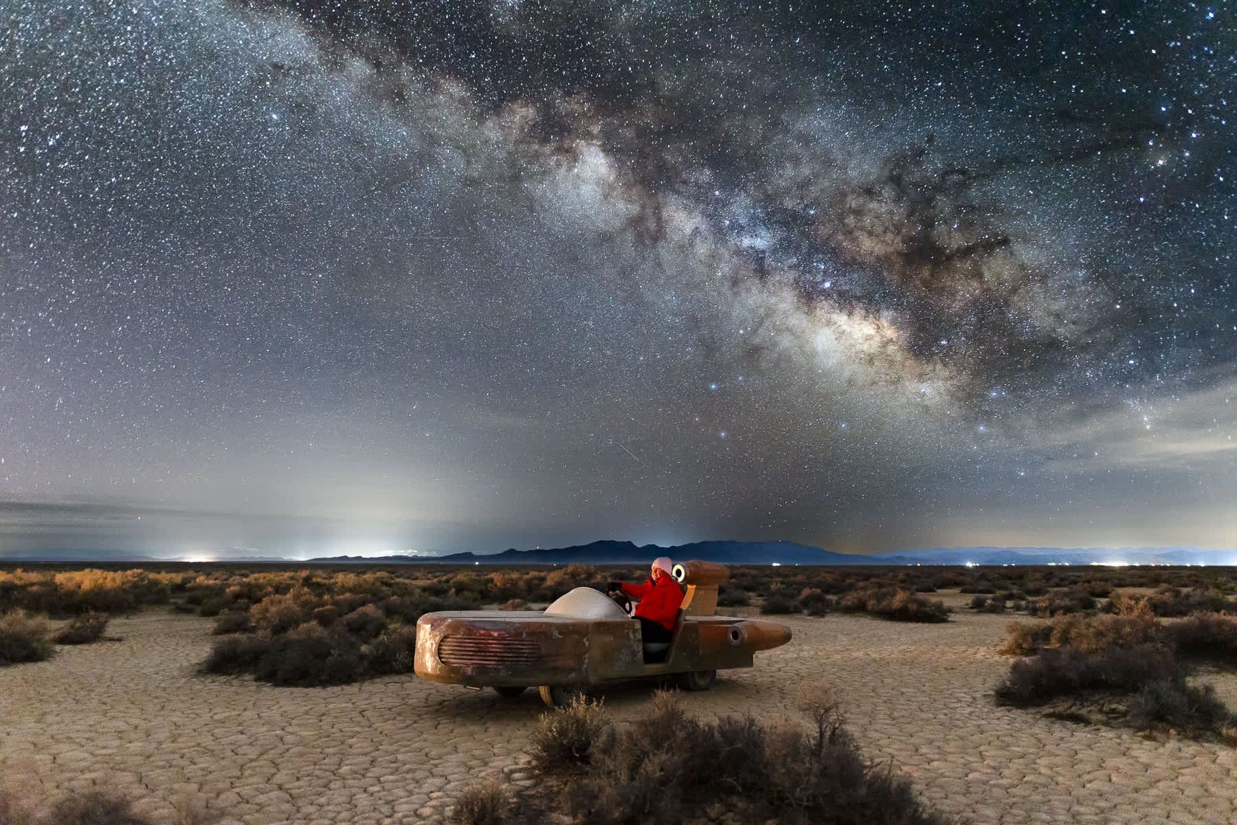 A person is sitting on a bench under a starry night sky.
