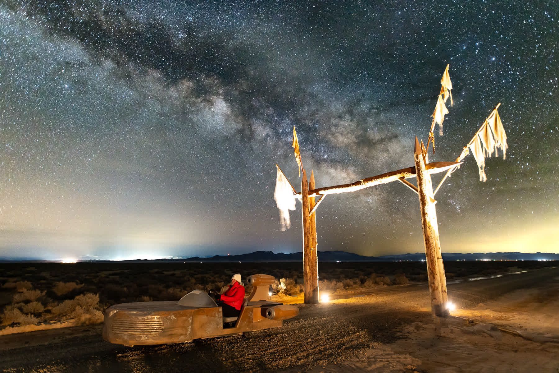 A person is sitting on a bench under a starry night sky.