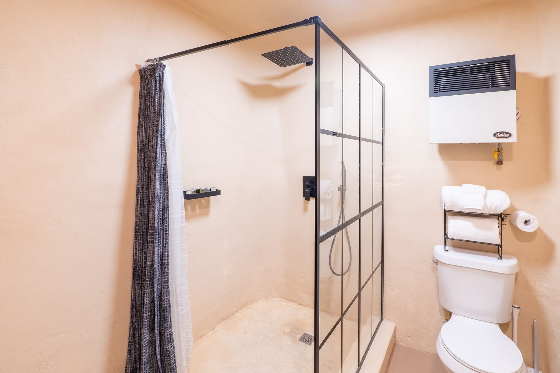 A bathroom with a toilet , shower , and towel rack.