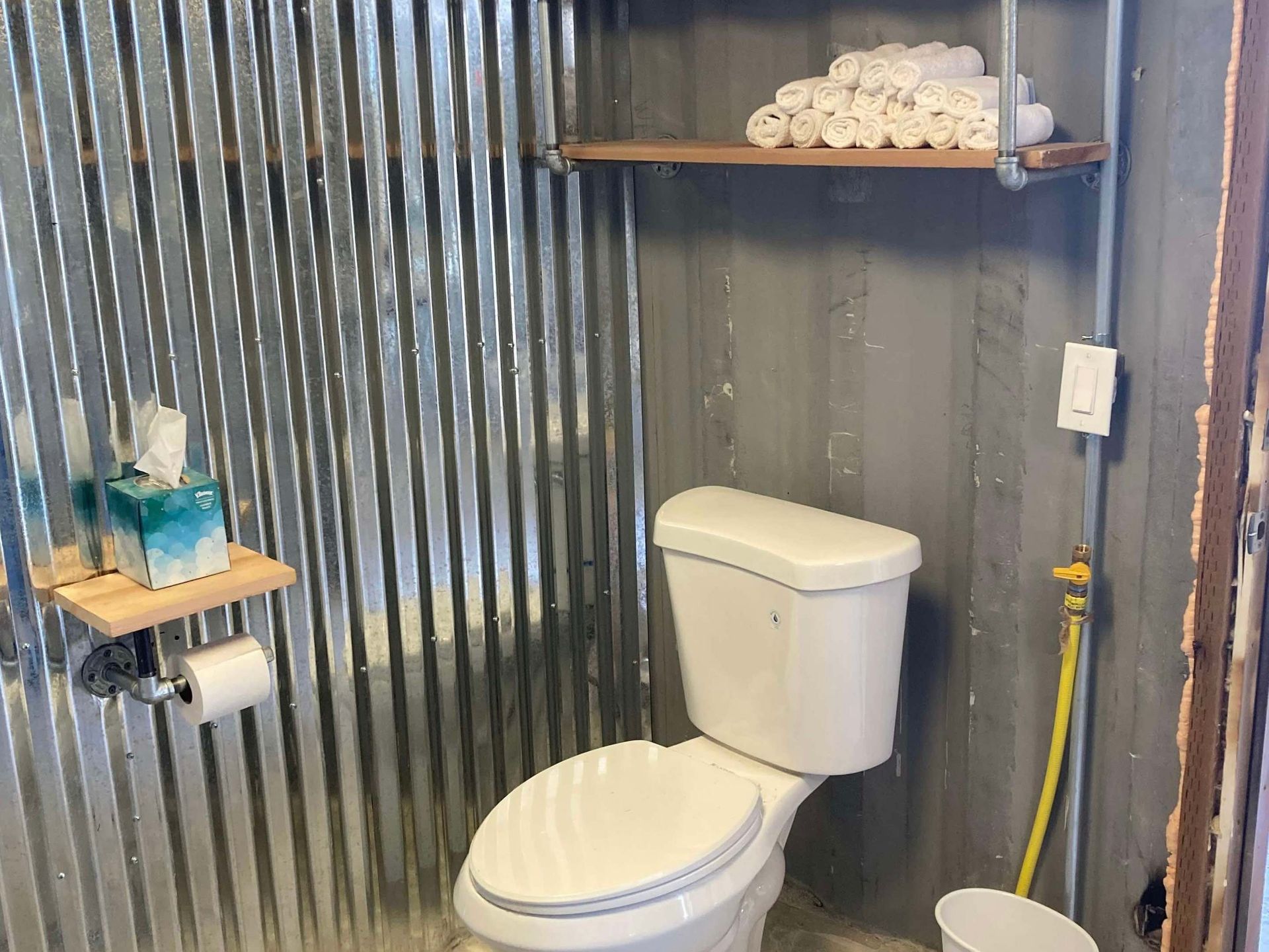 A bathroom with a toilet and a shelf with towels on it.