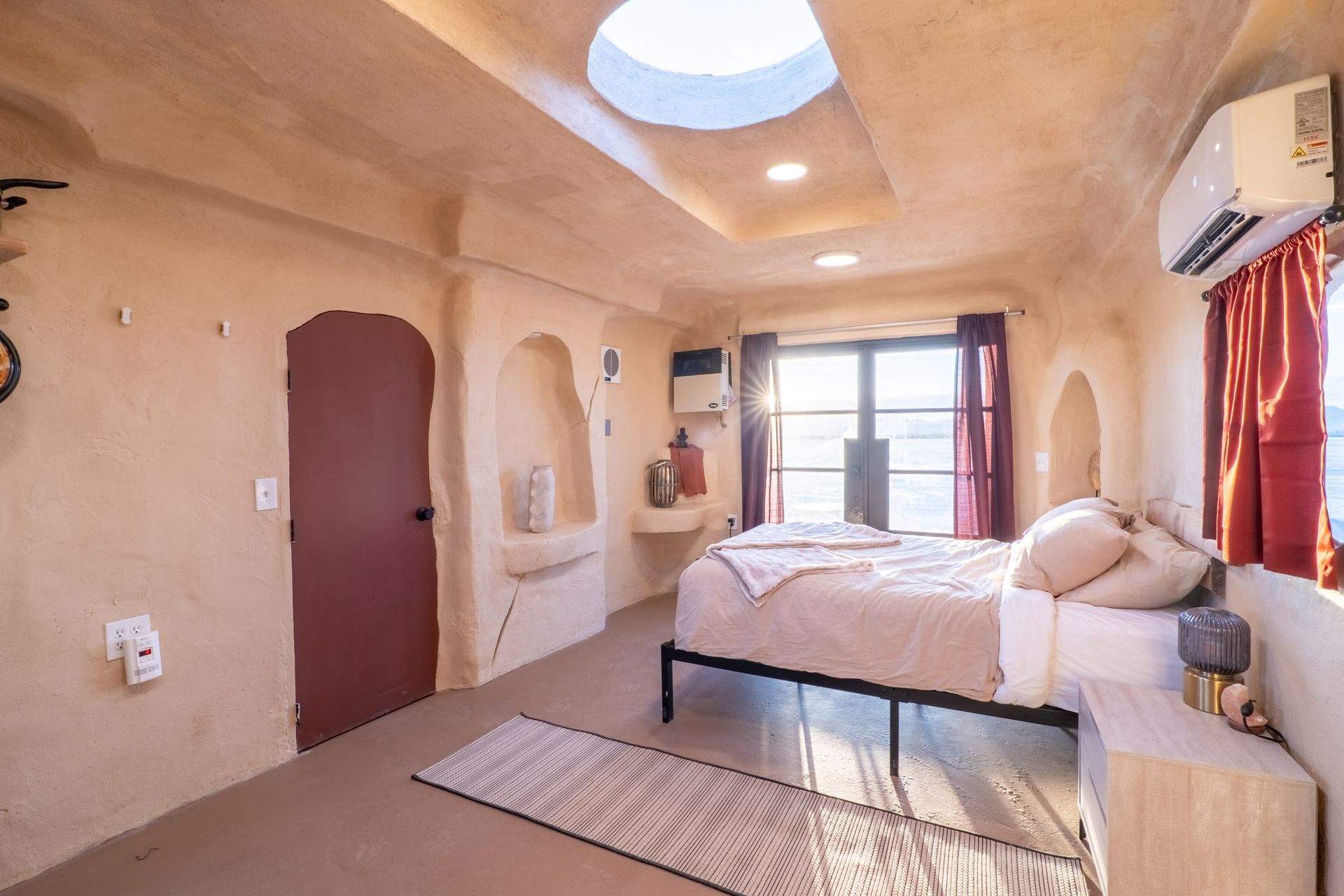 There is a bed in the middle of the room with a skylight in the ceiling.