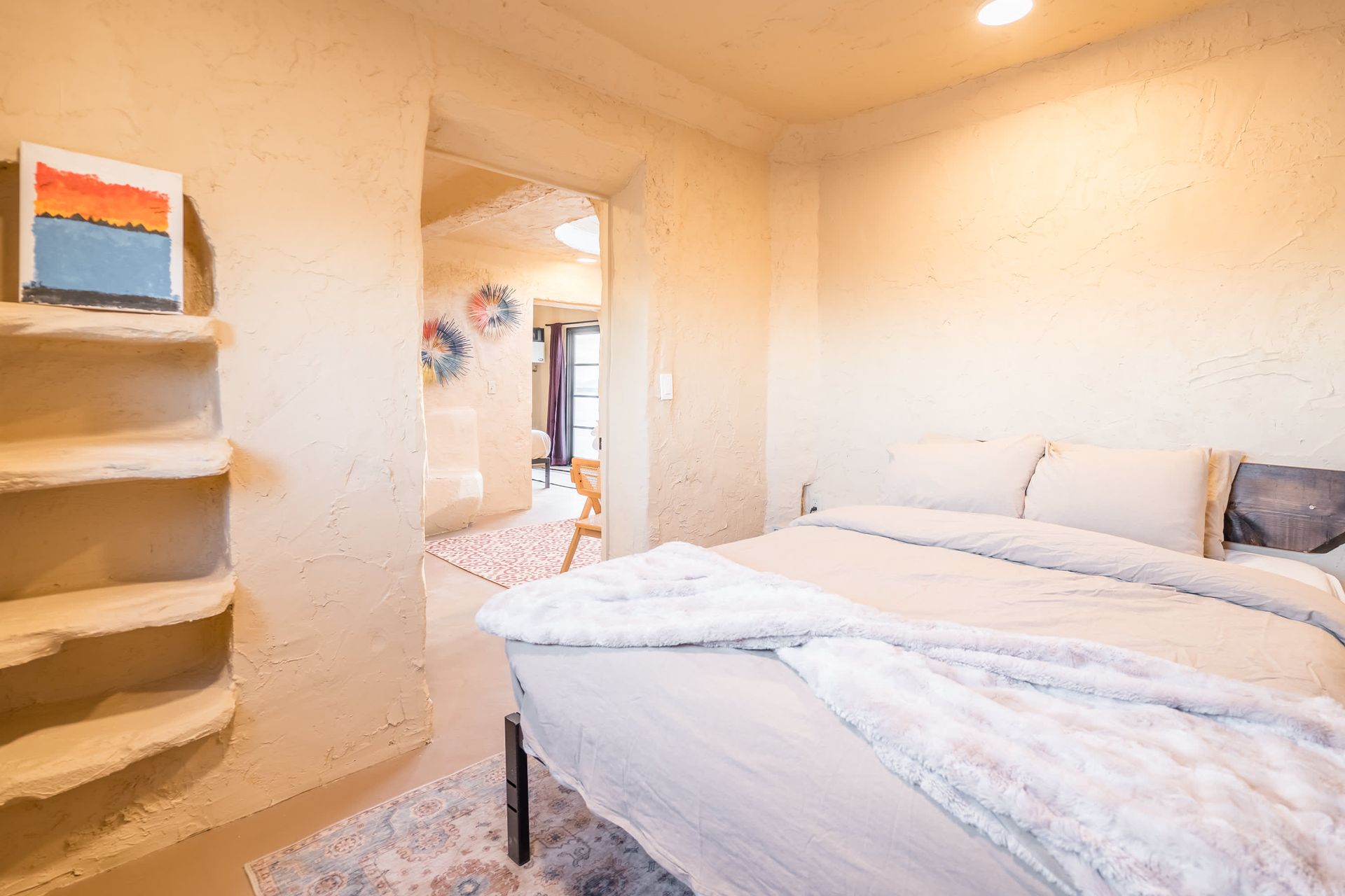A bedroom with a bed and a painting on the wall.