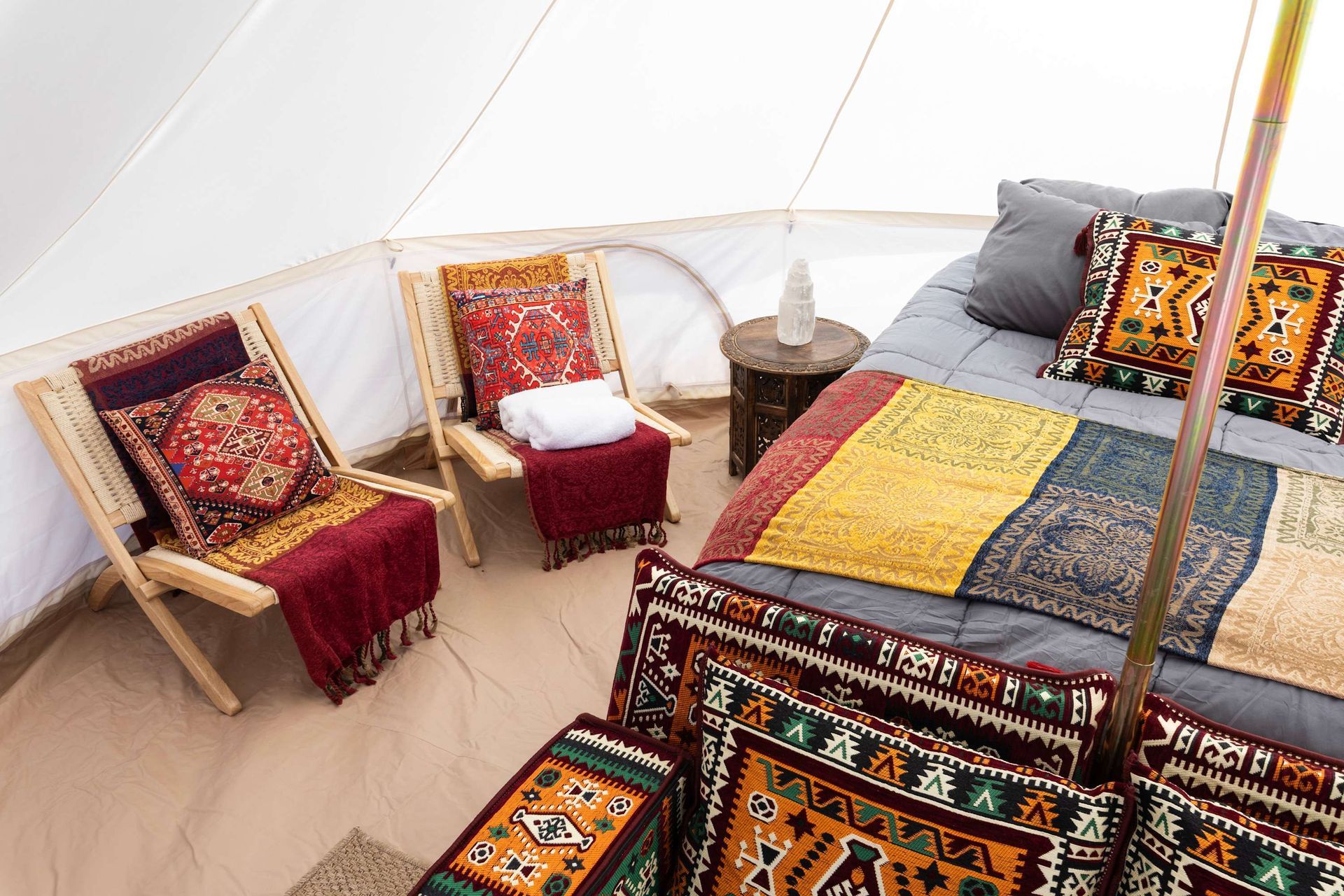 A bedroom in a tent with a bed , chairs and a rug.
